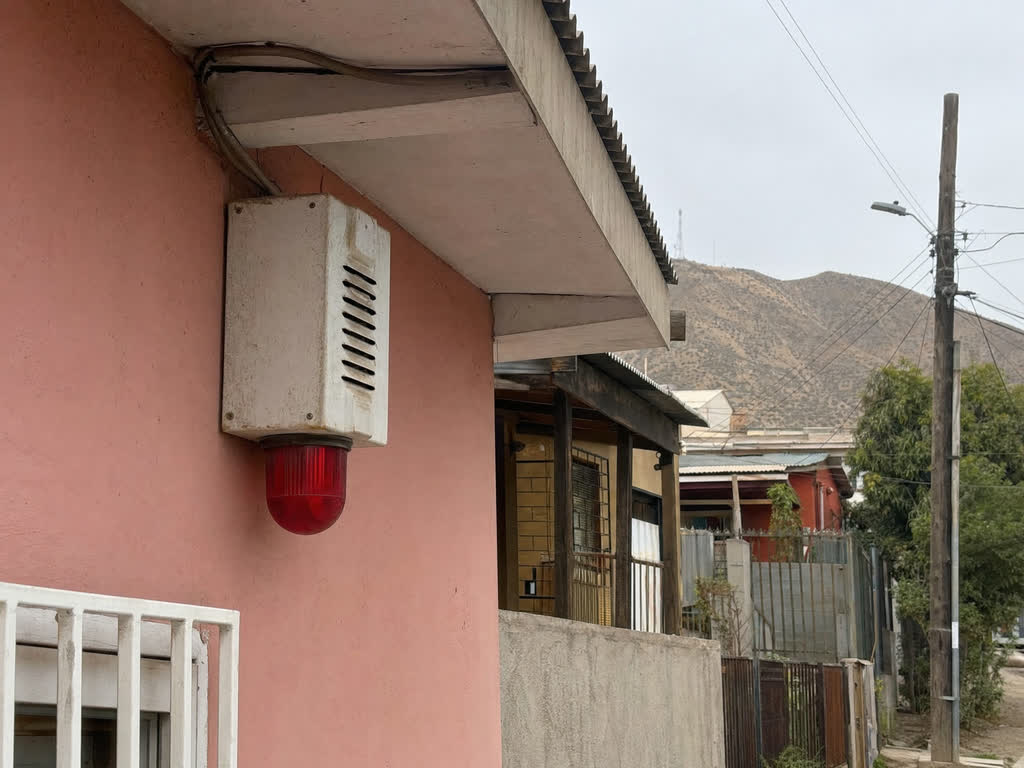 Sirena de alarma comunitaria instalada en la fachada de una vivienda