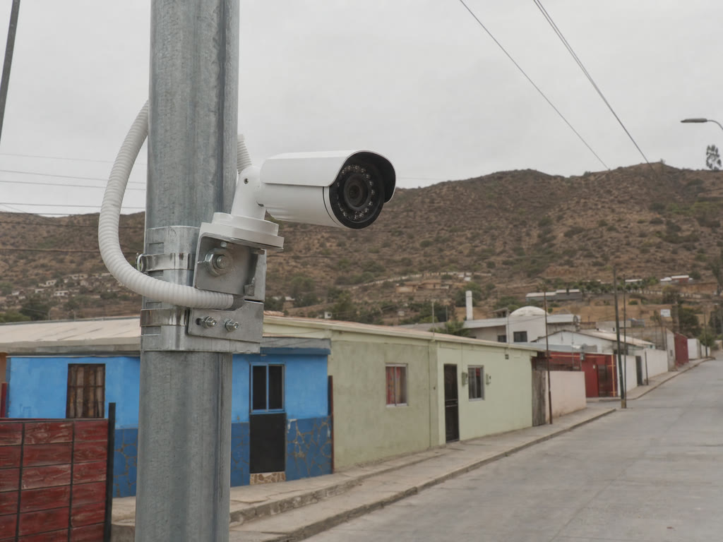 Cámara de seguridad tipo bala montada en un poste sobre una calle residencial